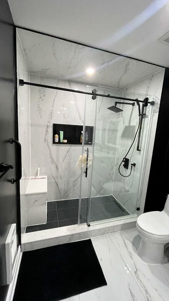 Finished walk-in shower with full marble tile and frameless glass